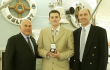 Medal of Excellence winner Colin Sanders is presented with his award aboard HMS Belfast